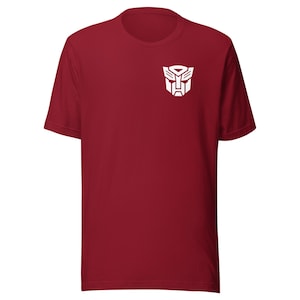 Op de afbeelding: Een rood T-shirt met een wit Transformers-logo op de voorkant.