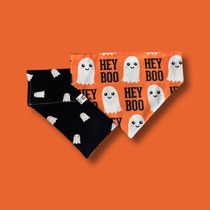 May include: Two dog bandanas, one black with white ghost silhouettes and the other orange with white ghosts and the text "Hey Boo" repeated.