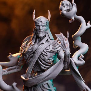 Op de afbeelding: Een grijze fantasiefiguur die een skeletachtige figuur met hoorns en vloeiende gewaden afbeeldt, die een schedel vasthoudt en omringd is door wervelende ranken. Een knielende figuur staat hieronder. De tekst "PATREON HELL CREATOR" staat onderaan.