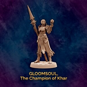 Può includere: Una statuetta in miniatura di una guerriera che tiene una lancia e un globo luminoso. La statuetta è dipinta di un colore marrone chiaro e si trova su una base circolare. Il testo "GLOOMSOUL, The Champion of Khar" è scritto sotto la statuetta.
