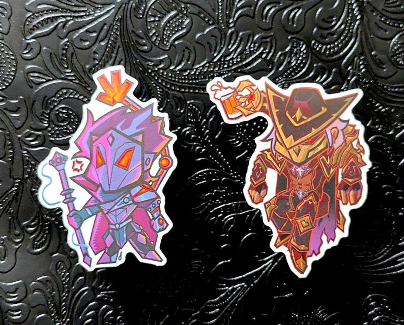 May include: Two stickers featuring stylized fantasy characters. One is a purple and blue mage with a staff, the other a red and gold armored figure with a beer stein. Both have a cartoonish design.