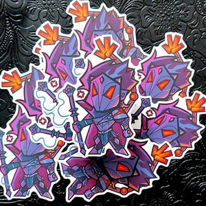 May include: A collection of stickers featuring a stylized, cartoonish character in purple, blue, and orange armor. The character holds a staff and has a geometric design. The stickers have a white border and are arranged on a black, textured surface.