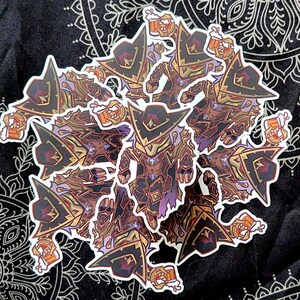 May include: A collection of stickers featuring a cartoon character in a dark hat and armor, holding a mug of beer. The stickers have a detailed design with brown, gold, and purple accents, and white borders. The stickers are on a black background.