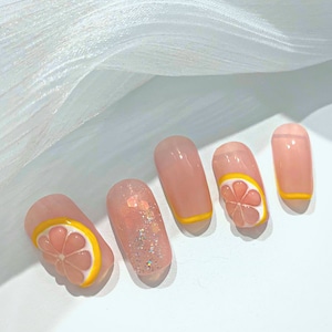 May include: Close-up of five pink and nude nails with yellow and pink lemon slice designs. Some nails have glitter.