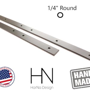 May include: Two silver metal strips with evenly spaced holes, each strip is 1/4 inch round. The strips are on a white background. The text "1/4" Round" is above the strips. The text "HN" is below the strips. The text "HarNa Design" is below "HN". A red, white, and blue American flag is in a circle with the text "Premium Quality" above the flag and "Made in USA" below the flag. The text "HAND MADE" is in a black rectangle with a gray background.