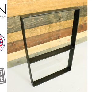 May include: Black metal table legs with a shelf. The legs are against a wood background.