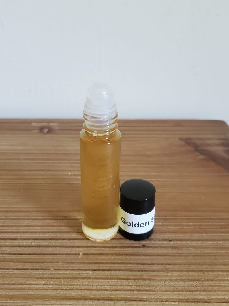 May include: A clear glass roller bottle with a white roller ball and a black cap. The cap has a white label with the text "Golden S" printed on it.