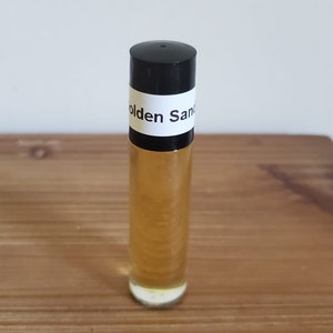 May include: A clear glass roll-on bottle with a black cap and a white label that reads "Golden Sand".