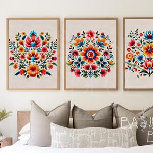 May include: Three framed prints featuring colourful floral designs. The flowers are red, orange, yellow, blue, green and pink. The background of the prints is a light beige.