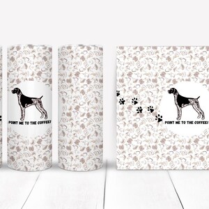 May include: A set of three white tumblers and a square coaster featuring a repeating pattern of coffee beans and paw prints. Each tumbler has a design of a dog and the text "POINT ME TO THE COFFEE!"