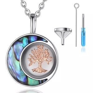 Pu&ograve; includere: Una collana d'argento con un ciondolo rotondo che presenta una luna crescente in madreperla di abalone e un design ad albero della vita. Il ciondolo ha una piccola apertura per aggiungere ceneri o altri ricordi. La collana viene fornita con un imbuto e un cacciavite per riempire il ciondolo.