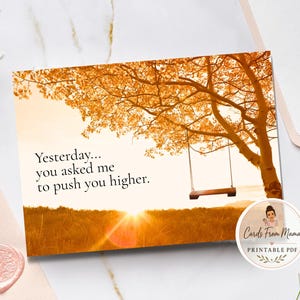 May include: A rectangular greeting card featuring an autumn landscape with a large tree, a wooden swing, and a sunset. The text reads: Yesterday... you asked me to push you higher. The card has a warm orange and yellow color palette with a soft glow.