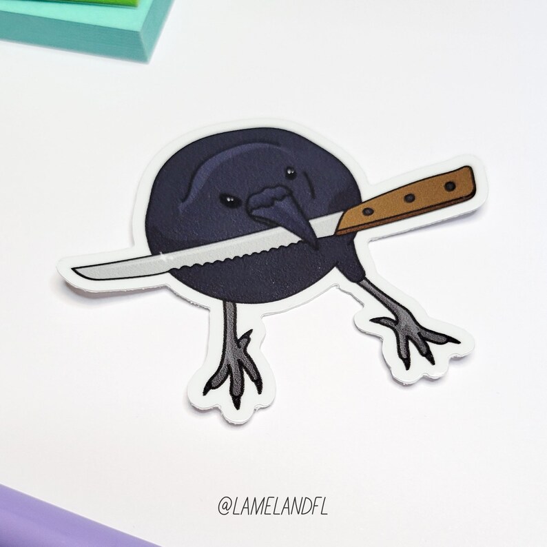 May include: A black crow with a knife in its beak. The crow is holding the knife in a menacing way. The crow is a sticker with a white background.