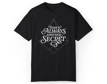 May include: Black t-shirt with a white graphic design of a geometric shape with the text "There's Always Another Secret" inside.