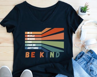 I en värld där du kan vara vad som helst, var snäll | Bella-Canvas djup v-ringad t-shirt