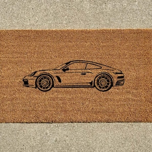 May include: A brown coir doormat with a black silhouette of a sports car.