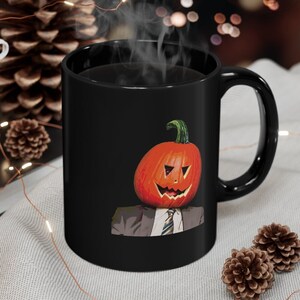 May include: Black coffee mug with a pumpkin head wearing a suit and tie. The pumpkin has a carved jack-o'-lantern face.