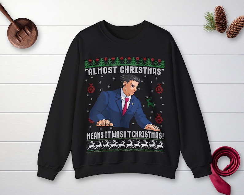 May include: A black crewneck sweatshirt featuring a graphic of a character in a blue suit and red tie. The text reads "ALMOST CHRISTMAS" and "MEANS IT WASN'T CHRISTMAS!" surrounded by green pine trees, red ornaments, and white reindeer patterns.