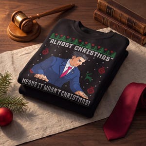 May include: A black crewneck sweatshirt featuring a graphic of a character in a blue suit and red tie pointing forward. The text reads "ALMOST CHRISTMAS" and "MEANS IT WASN'T CHRISTMAS!" surrounded by green pine trees, red ornaments, and snowflakes.