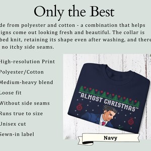 May include: A navy blue crewneck sweatshirt featuring a graphic print of a character in a suit with the text "ALMOST CHRISTMAS" above, surrounded by a pattern of green pine trees and red ornaments. The garment has a ribbed knit collar.