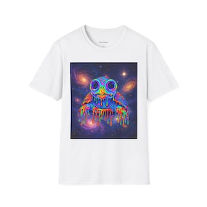 May include: White t-shirt featuring a vibrant, psychedelic turtle design. The turtle has large, colorful eyes and a rainbow-colored, dripping effect. The background is a swirling galaxy of purples, blues, and pinks, with stars and nebulae.
