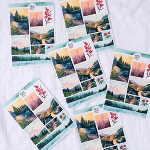 May include: A set of six watercolor stickers featuring a mountain landscape with a river, trees, and a deer. The stickers are printed on white paper and have a glossy finish. The stickers are perfect for adding a touch of nature to your planner, journal, or scrapbook.