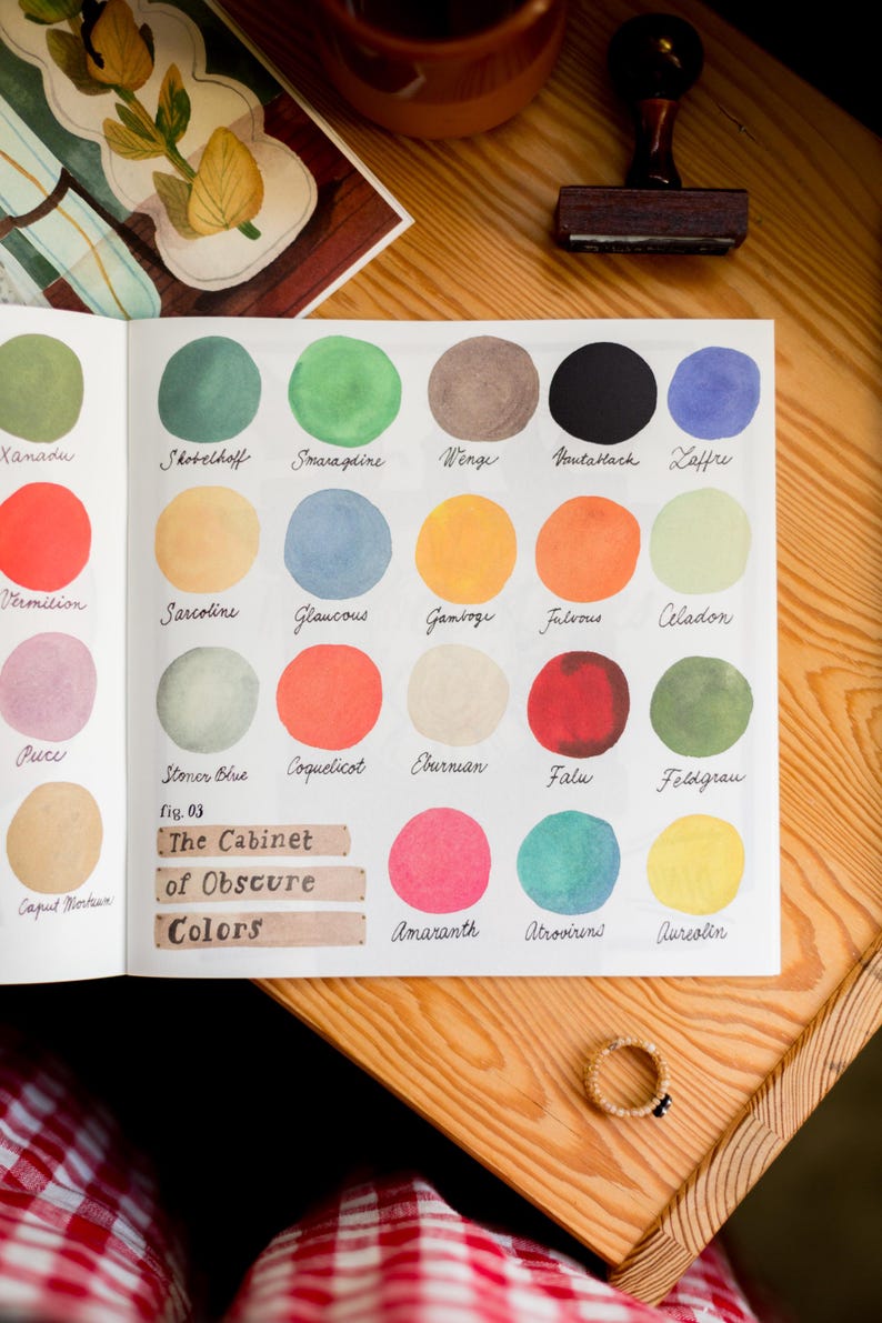 May include: A page from a book titled "The Cabinet of Obscure Colors" with a color chart of 18 different watercolor paint swatches. Each swatch is labeled with a color name, such as "Xanadu", "Shobelhoff", "Smaragdine", "Wenge", "VantaHack", "Laffre", "Vermilion", "Sarcoline", "Glaucous", "Gamboge", "Fulvous", "Celadon", "Puce", "Stoner Blue", "Coquelicot", "Eburnian", "Falu", "Feldgrau", "Amaranth", "Atrovirens", and "Aureolin".