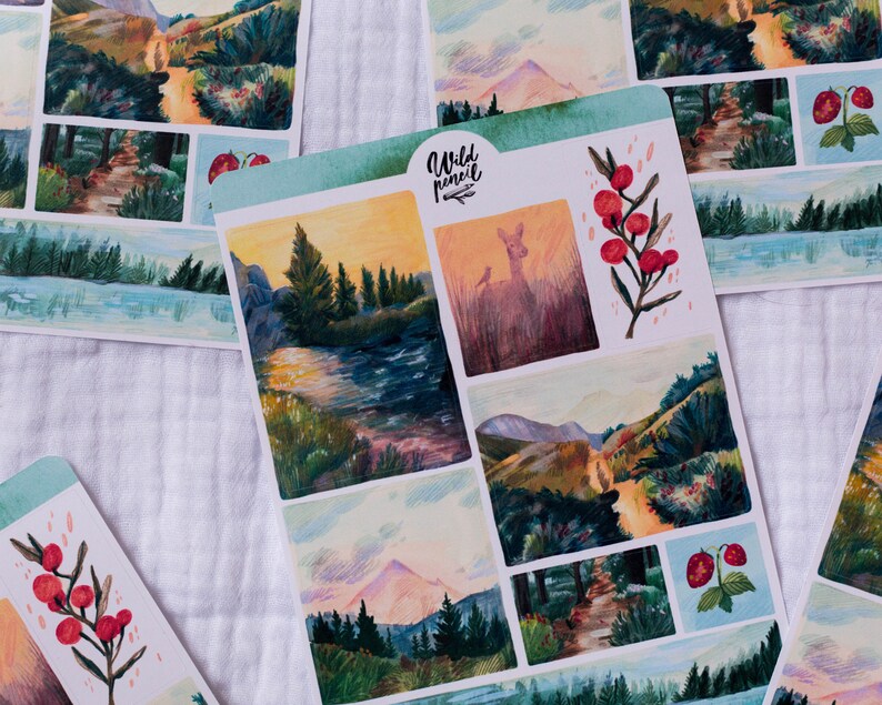 May include: A sheet of stickers featuring watercolor illustrations of nature scenes. The stickers include a deer in a forest, a mountain range, a river, and a path through a forest. The stickers are printed on white paper with a light blue border.