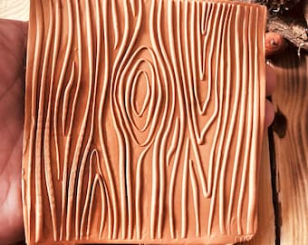 May include: A brown rubber stamp with a wood grain design. The stamp is approximately 3 inches by 3 inches.