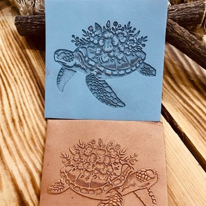 May include: Two rubber stamps, one blue and one brown, with a detailed design of a sea turtle with a floral crown on its head.