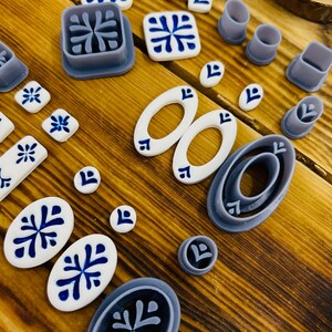 May include: A set of 17 blue and white ceramic tile molds. The molds are in various shapes, including squares, ovals, and circles. The molds are made of a durable plastic material and are perfect for creating beautiful and unique tiles.