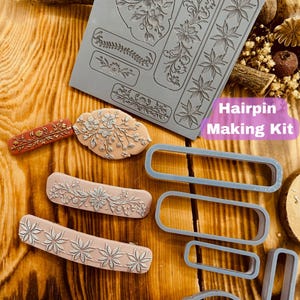 May include: A set of silicone molds for making hairpins. The molds feature various floral designs and a leaf shape. There are also three rectangular molds for creating the hairpin base. The set includes a sample hairpin with a floral design.