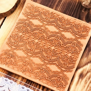 May include: A brown rubber stamp with three rows of intricate lace designs. The stamp is on a wooden surface.