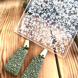 Op de afbeelding: Een paar groene en gouden oorhangers met een bladmotief. De oorhangers zijn gemaakt van polymer clay en hebben een gouden haak.