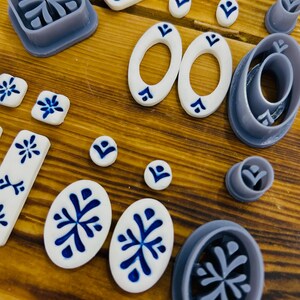 May include: A set of 10 polymer clay cutters in various shapes and sizes, including circles, ovals, and squares. The cutters are designed with a snowflake pattern and are perfect for creating decorative accents for crafts.