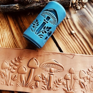 May include: A blue silicone roller with a mushroom and leaf design. The roller is used to create an embossed pattern on clay or polymer clay.