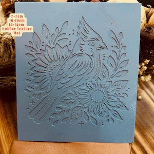 Puede incluir: Alfombra de textura de goma azul con un diseño en relieve de un pájaro y flores. La alfombra mide 7-7cm, 10-10cm, 14-14cm.