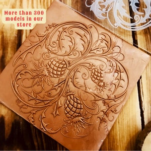 May include: A close-up of a brown leather stamp with a detailed design of three thistles with intricate floral patterns. The stamp is on a wooden surface. The text "More than 300 models in our store" is visible in the top left corner of the image.