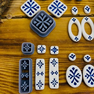 May include: A set of 16 blue and white ceramic tile cookie cutters. The cutters are in various shapes, including squares, rectangles, ovals, and circles. The cutters are made of durable plastic and are perfect for creating decorative cookies.