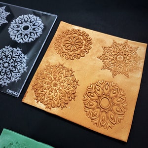 May include: A clear plastic sheet with four mandala designs, used to create impressions in leather. The sheet is labeled "CNS147".  A piece of brown leather with four embossed mandala designs is shown next to the sheet.
