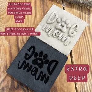 Può includere: Due timbri quadrati, uno grigio chiaro e uno grigio scuro, con le parole "Dog Mom" e un disegno a zampa. Il timbro grigio chiaro ha un rilievo di 5 mm e un'altezza del materiale di 10 mm. Il timbro grigio scuro è etichettato "Extra Deep".