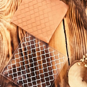 May include: Two square silicone stencils with a grid pattern. The top stencil is brown and the bottom stencil is clear with a white grid pattern. The bottom stencil has the text "CNS062" printed on it.