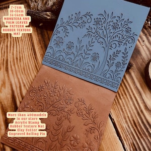 Può includere: Due tappetini in gomma con texture e motivo floreale. Il tappetino superiore è blu e quello inferiore è marrone. I tappetini misurano 7 cm x 7 cm, 10 cm x 10 cm e 14 cm x 14 cm. Il testo sul tappetino recita "Monstera and Palm Leaves Pattern Rubber Texture Mat".