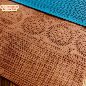 以下が含まれることがあります： 複雑なパターンが施された茶色のゴム製テクスチャマット。小さな花が繰り返し描かれたデザインと、花柄のディテールが施された大きな円形デザインが含まれています。マットには「10-14cm Rubber Texture Mat」とラベルが貼られています。