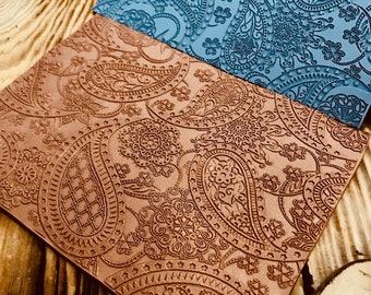 May include: Two pieces of leather with a paisley pattern. One piece is brown and the other is blue.