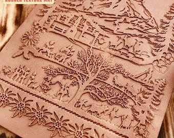 Könnte beinhalten: Eine braune Gummi-Texturmatte mit detailliertem Reliefdesign. Die Matte zeigt eine Berglandschaft, einen Baum und Figuren von Menschen und Tieren. Der Text "IO-14CM RUBBER TEXTURE MAT" ist sichtbar. Die Matte misst 10-14 cm.