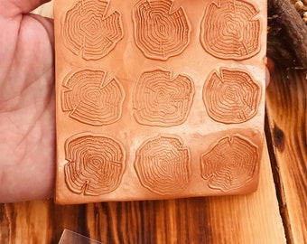 May include: A silicone mold with nine impressions of tree rings. The mold is a light brown color and is sitting on a wooden surface.