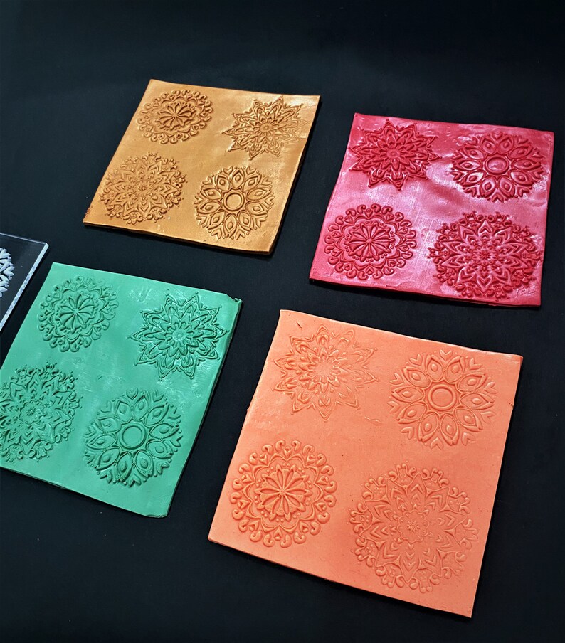 May include: Four silicone mats with different mandala designs. The mats are in gold, red, green, and orange.