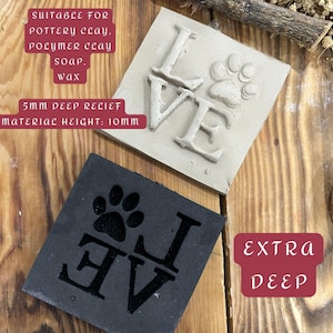May include: Two square stamps, one light gray and one black, with the word "LOVE" and a paw print. The light gray stamp has a 5mm deep relief and a material height of 10mm. The stamps are suitable for pottery clay, polymer clay, soap, and wax.