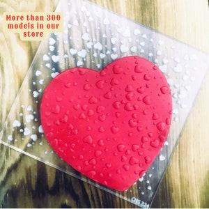 May include: A red heart-shaped silicone mold with a pattern of small hearts. The mold is on a clear plastic sheet with a white background. The text "More than 300 models in our store" is visible in the top left corner of the image.